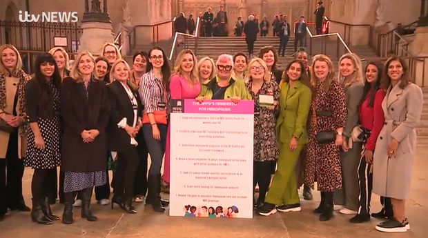 A group photo of women posing with the menopause manifesto. Dawn Owen is stood just off centre right, holding a FTWW leaflet